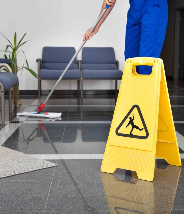 Close-up Of Man Cleaning The Floor With Yellow Wet Floor Sign